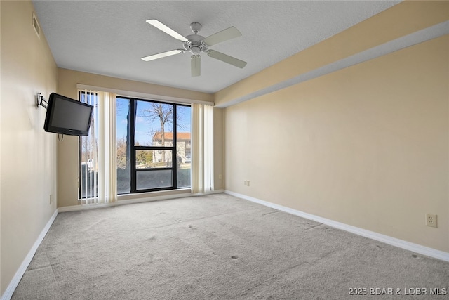 spare room with visible vents, ceiling fan, baseboards, carpet, and a textured ceiling