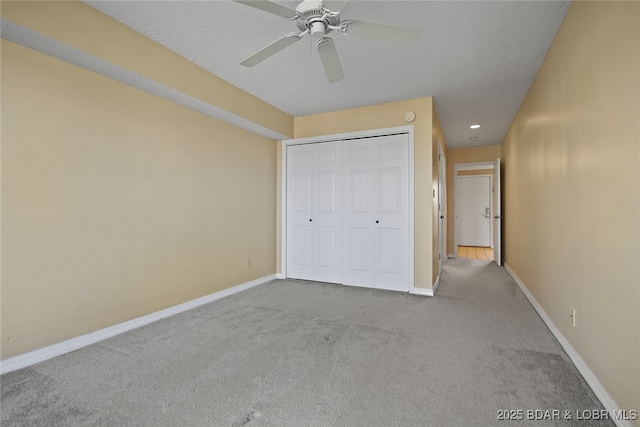 unfurnished bedroom featuring a ceiling fan, carpet, baseboards, a closet, and a textured ceiling