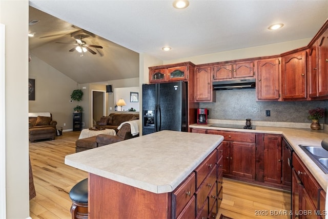 kitchen with under cabinet range hood, light wood-style floors, black appliances, and open floor plan