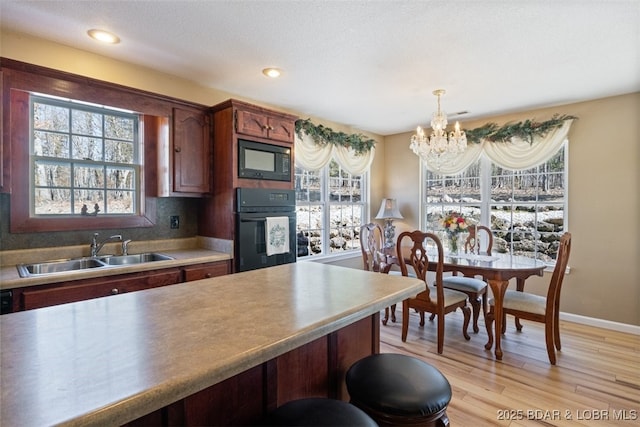 kitchen with a notable chandelier, a healthy amount of sunlight, black appliances, and a sink