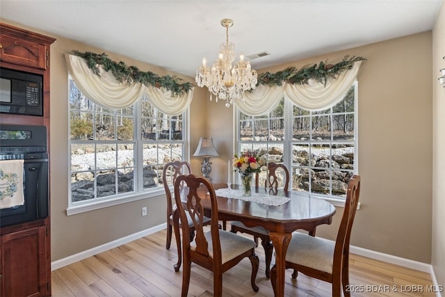 dining room featuring light wood-style flooring, baseboards, and a chandelier