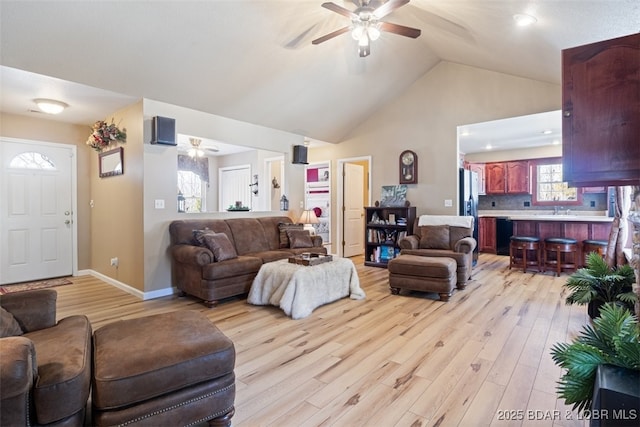 living area with light wood-style flooring, baseboards, high vaulted ceiling, and ceiling fan