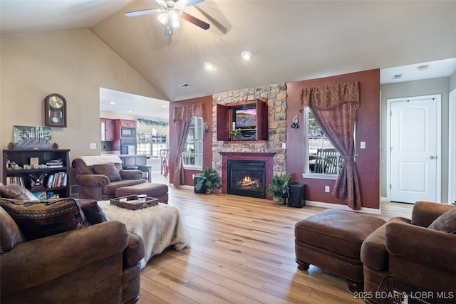 living room with light wood finished floors, visible vents, baseboards, a fireplace, and high vaulted ceiling