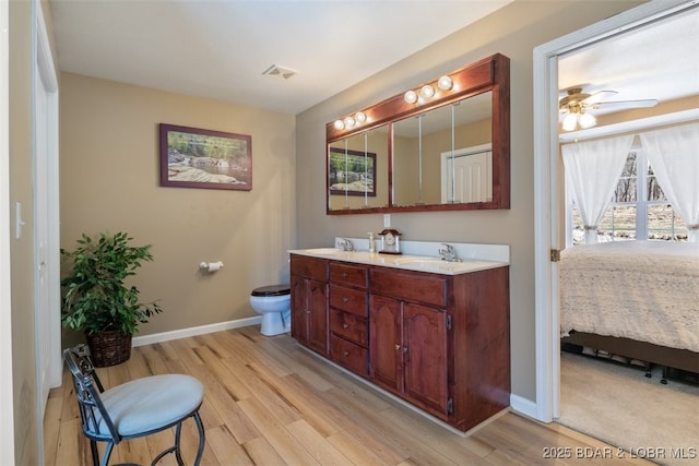 ensuite bathroom with ensuite bath, wood finished floors, visible vents, and a sink