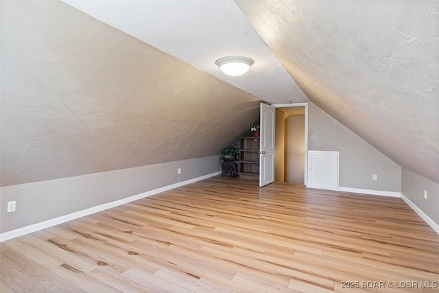 bonus room with baseboards, lofted ceiling, and wood finished floors