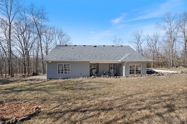 back of property with a lawn and a shingled roof