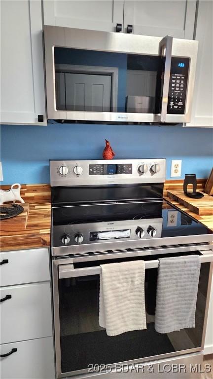 kitchen featuring wood counters, white cabinets, and stainless steel appliances