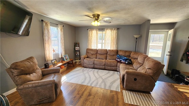 living room featuring baseboards, a textured ceiling, wood finished floors, and a ceiling fan