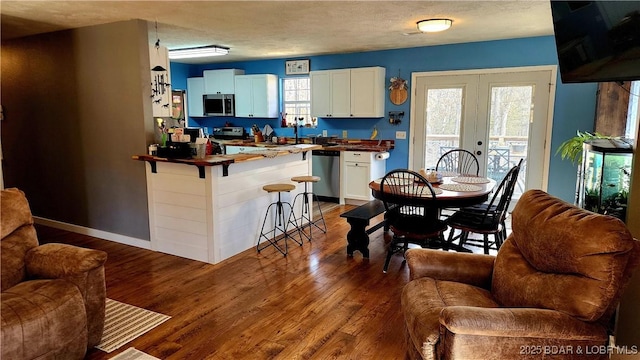 dining area featuring dark wood finished floors, french doors, baseboards, and a textured ceiling