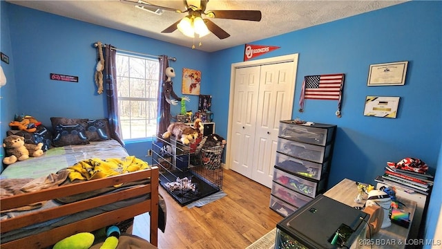 bedroom with a closet, a textured ceiling, a ceiling fan, and wood finished floors