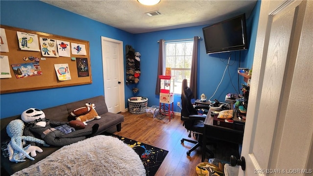 office area featuring visible vents, baseboards, a textured ceiling, and wood finished floors