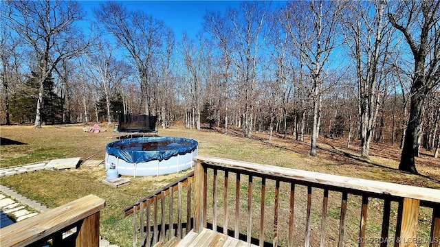 view of yard with a trampoline and a deck