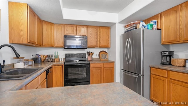 kitchen with black appliances, a tray ceiling, and a sink