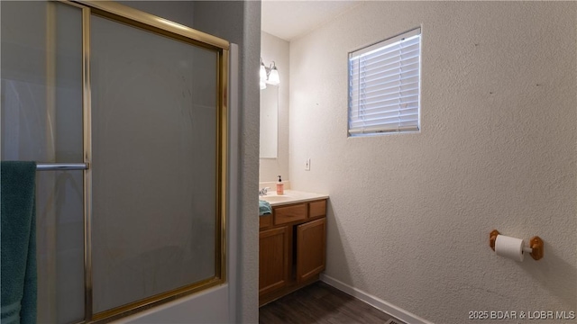 bathroom featuring a shower with door, vanity, a textured wall, and wood finished floors