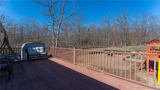 wooden terrace featuring an outbuilding, a playground, and a shed