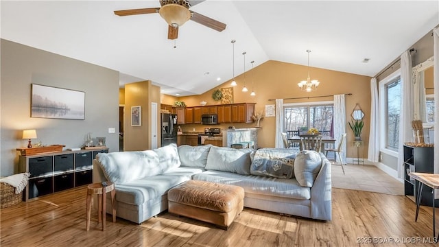 living area featuring light wood-type flooring, visible vents, ceiling fan with notable chandelier, baseboards, and vaulted ceiling