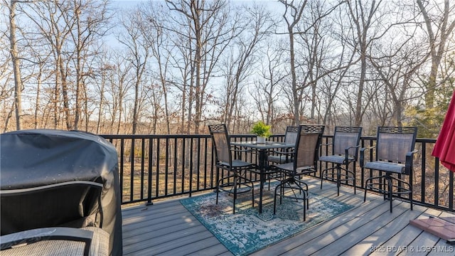 wooden deck with outdoor dining space and grilling area