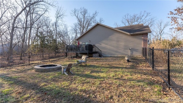 view of property exterior with a deck, a fenced backyard, brick siding, and an outdoor fire pit