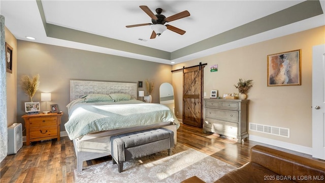 bedroom with visible vents, a barn door, baseboards, and wood finished floors