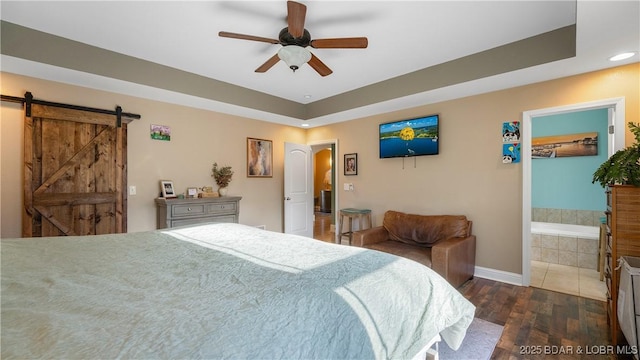 bedroom with a barn door, ensuite bathroom, wood finished floors, arched walkways, and a ceiling fan