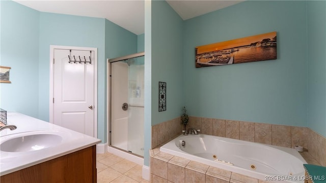 bathroom featuring tile patterned flooring, a tub with jets, a stall shower, and a sink