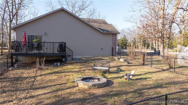 rear view of house with a yard, an outdoor fire pit, a deck, and fence