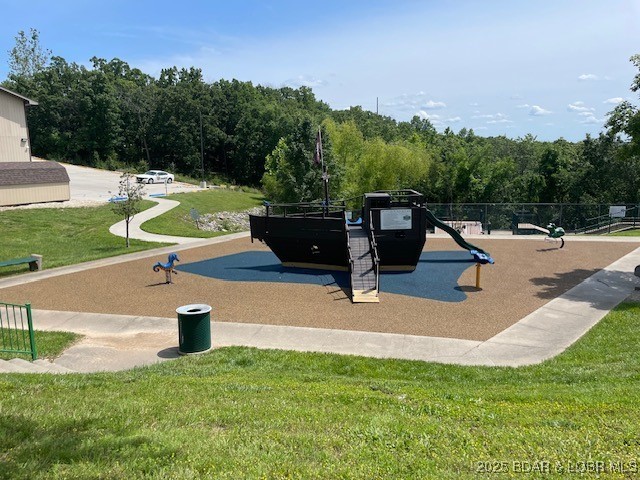 surrounding community with a wooded view, a yard, and playground community