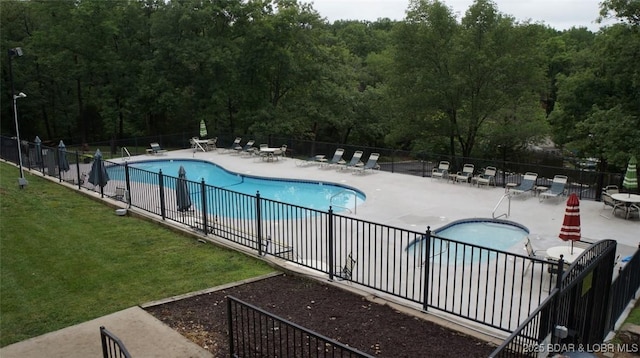 community pool with a yard, a patio, and fence