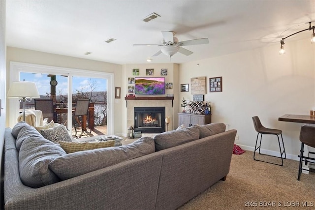 living area featuring visible vents, carpet flooring, baseboards, and a glass covered fireplace