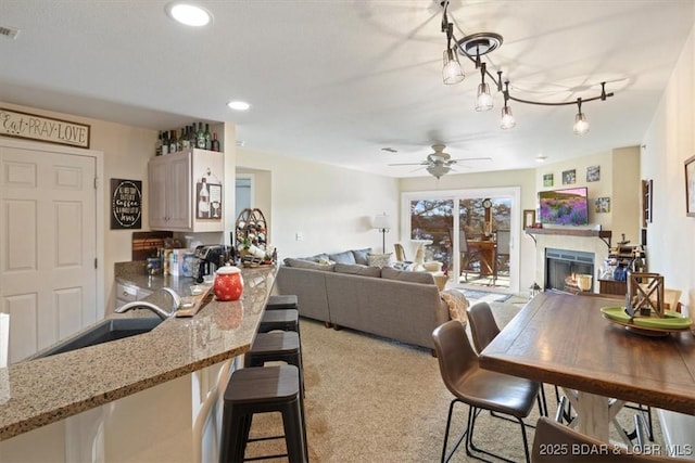 dining area with visible vents, a ceiling fan, a warm lit fireplace, recessed lighting, and light colored carpet