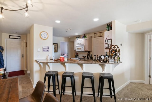 kitchen with white microwave, stone countertops, stove, and a kitchen bar