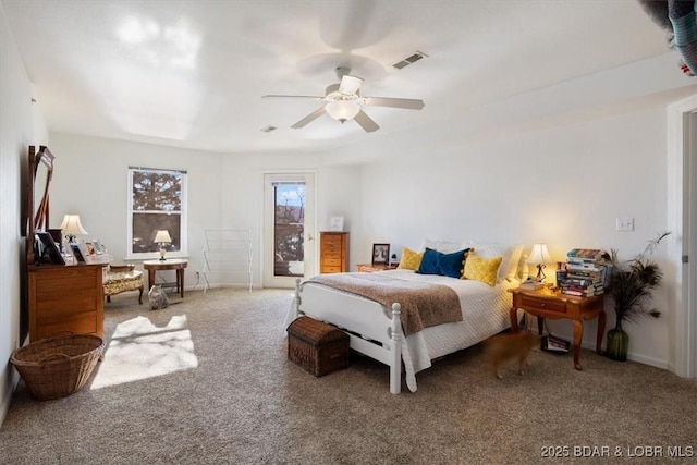 carpeted bedroom with access to exterior, a ceiling fan, and visible vents