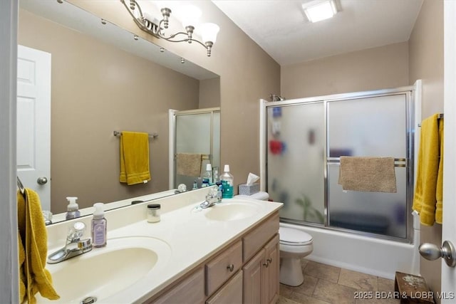 full bathroom featuring double vanity, shower / bath combination with glass door, toilet, and a sink