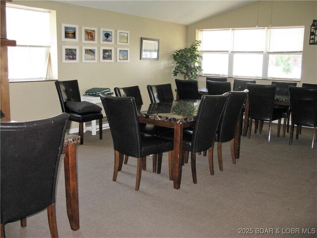 carpeted dining space featuring vaulted ceiling