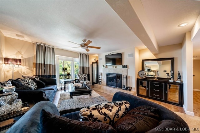 tiled living room with ceiling fan, a fireplace, visible vents, and baseboards