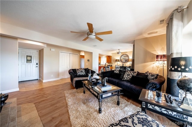 living area with visible vents, wood finished floors, baseboards, and ceiling fan