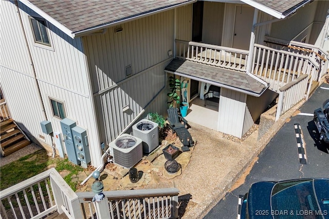 view of side of property with central air condition unit and a shingled roof