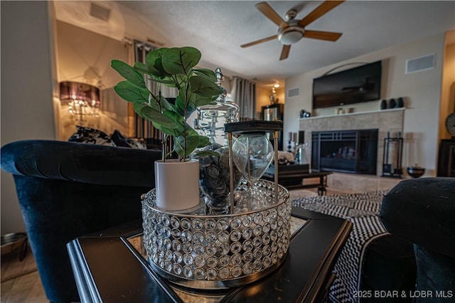 living area featuring visible vents, a tile fireplace, and ceiling fan