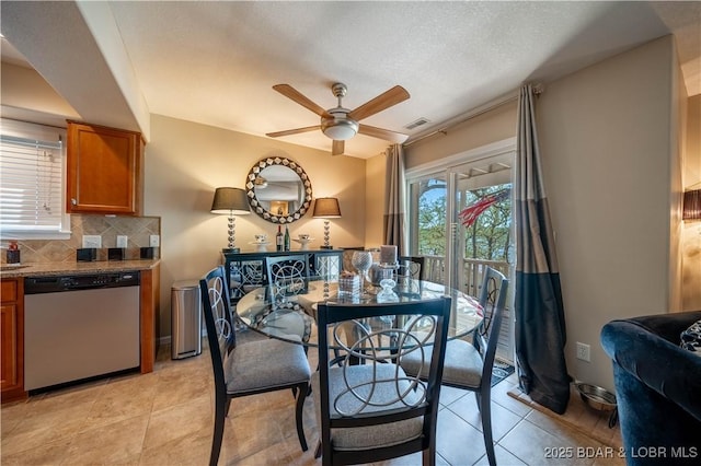 dining space with visible vents, a textured ceiling, light tile patterned flooring, baseboards, and ceiling fan