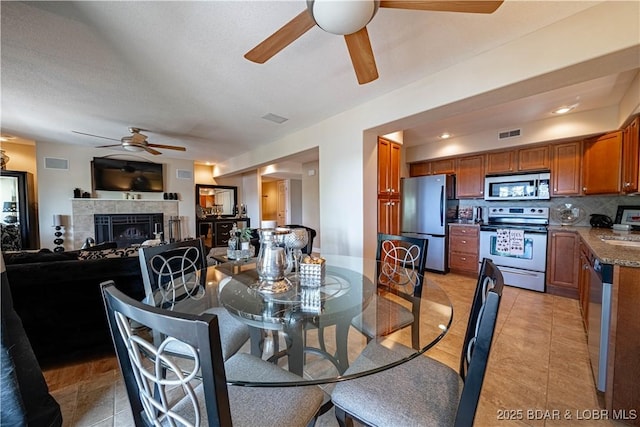 dining space featuring light tile patterned floors, visible vents, and a tile fireplace