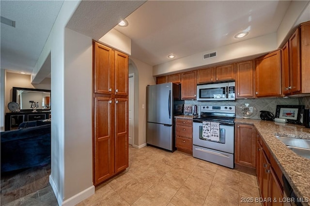 kitchen with brown cabinetry, visible vents, and appliances with stainless steel finishes