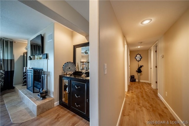 corridor with baseboards and light wood-style floors