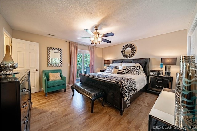 bedroom with wood finished floors, a textured ceiling, access to exterior, and a ceiling fan