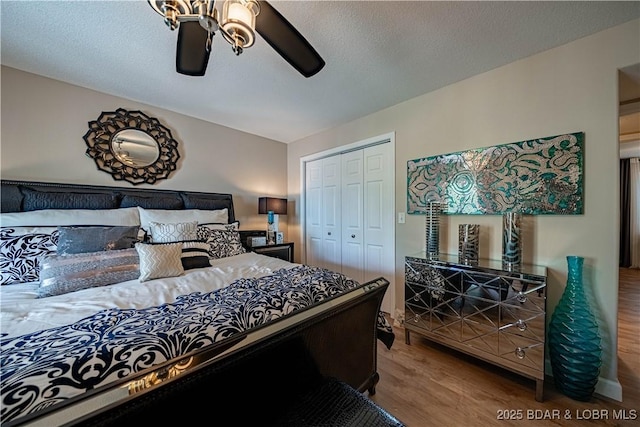 bedroom with a closet, a textured ceiling, ceiling fan, and wood finished floors