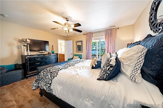 bedroom with a ceiling fan, wood finished floors, visible vents, and a textured ceiling