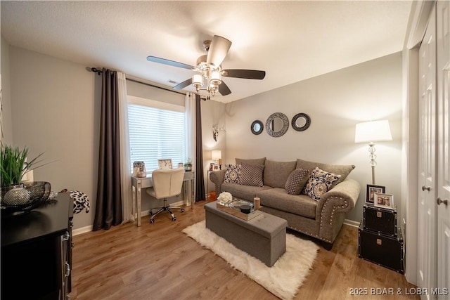 living area with baseboards, a ceiling fan, and wood finished floors