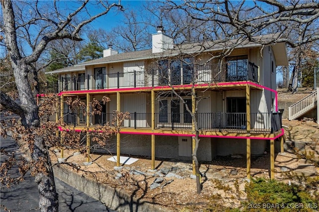 back of property with a balcony and a chimney