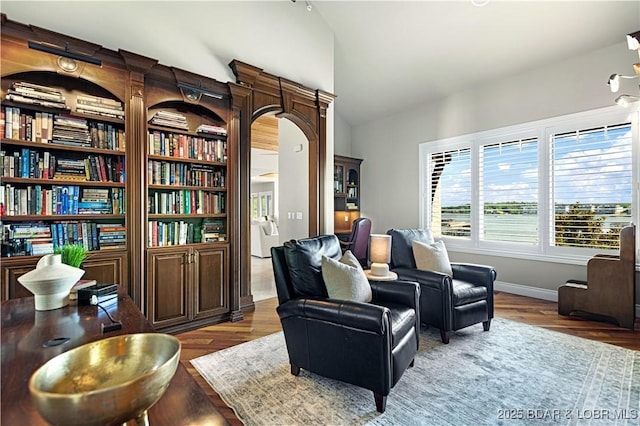 sitting room featuring baseboards, lofted ceiling, and wood finished floors