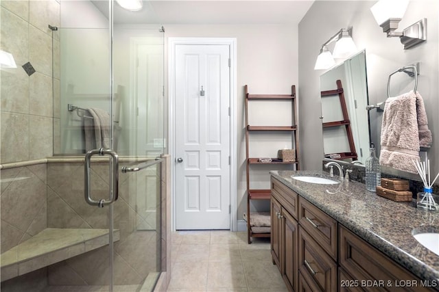 full bath with tile patterned floors, a stall shower, double vanity, and a sink