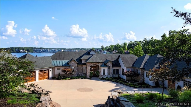 view of front of house with a garage, stone siding, and driveway